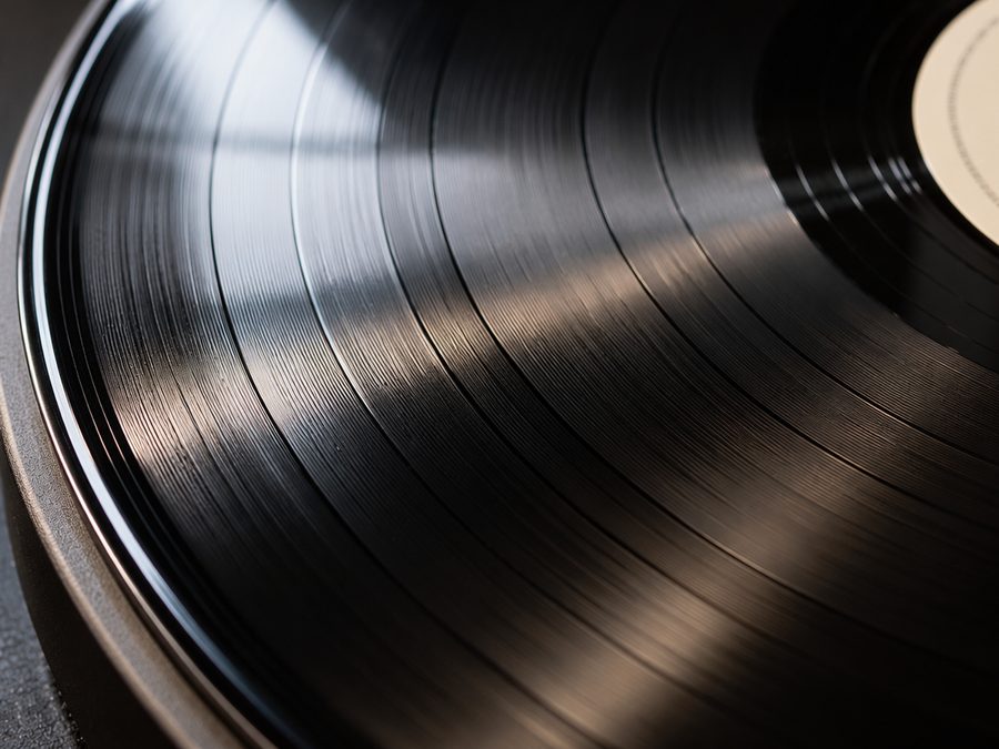 Primer plano de la superficie de un disco de vinilo sin marcas, con los surcos brillantes.